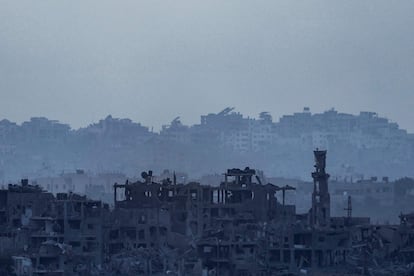Una bandera israelí ondea sobre los escombros de un edificio en ruinas de la Franja.