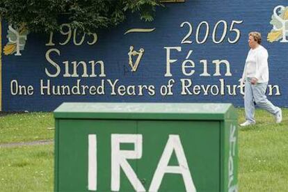 Una mujer pasa ante una pintada del IRA y otra de su rama política, Sinn Fein, ayer en Belfast.