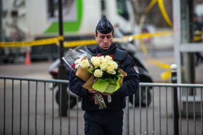 Un oficial de policía lleva flores al lugar del atentado en un mercado.