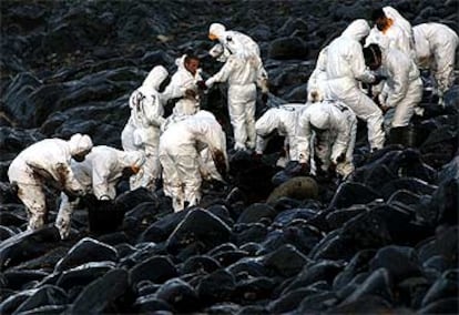 Un grupo de soldados se afanaba ayer en limpiar el fuel que cubre las rocas de la costa gallega cerca de Carnota.