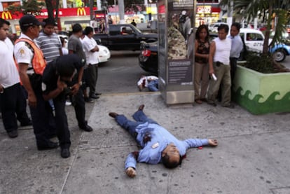 Los cuerpos sin vida de dos policías yacen tras ser tiroteados ayer en una de las calles céntricas de Acapulco.