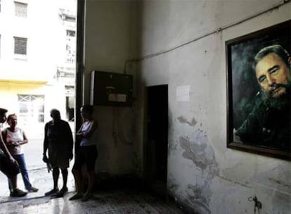 Vecinos de La Habana, en la puerta de un edificio, junto al retrato de Castro.