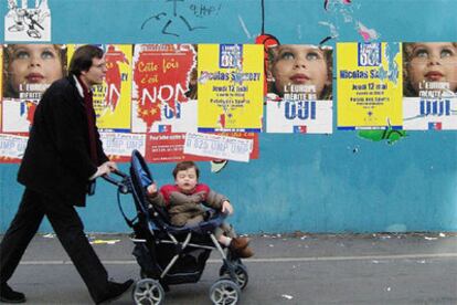 Un hombre pasea a su bebé entre carteles sobre el referéndum a la Constitución Europea.