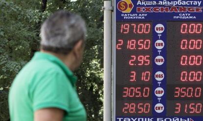 Un hombre observa un panel de cotizaciones del tenge en Almaty (Kazajistán).