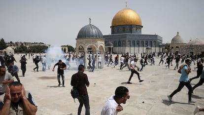 Decenas de palestinos corren tras el lanzamiento de granadas aturdidoras por agentes israelíes, este viernes en la Explanada de las Mezquitas de Jerusalén.
