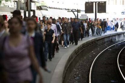 Un grupo de pasajeros camina por uno de los andenes de la estación de Saint-Lazare en París. El sector ferroviario ha sido hoy uno de los más afectados por la huelga convocada en Francia contra el retraso en la edad de jubilación.