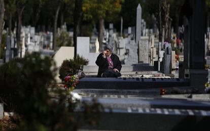 Una mujer llora frente a la lápida de un familiar en el cementerio madrileño de La Almudena.