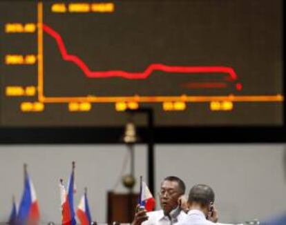 Corredores de bolsa filipinos hablan por teléfono jutno a un panekl electrónico de la Bolsa de Filipinas en el distrito financiero de Makati, Manila, Filipinas. EFE/Archivo