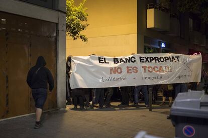Els 'okupes' mostren una pancarta contra el desallotjament que es va produir aquest dilluns al local de la travessera de Gràcia.