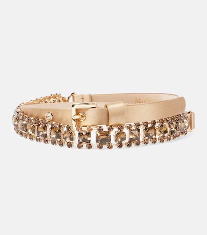 Confeccionado en un delicado tejido de viscosa y satén, este cinturón de Max Mara se combina con otro realizado en vidrio e color caramelo que captura la luz con elegancia. Su cierre regulable con hebilla metálica permite adaptarlo cómodamente, ya sea sobre prendas fluidas o marcando la cintura en estilismos más estructurados. (209 €)