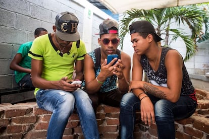 Tres jovenes conectados a Internet con sus móviles en el espacio de arte El Romerillo, en La Habana.