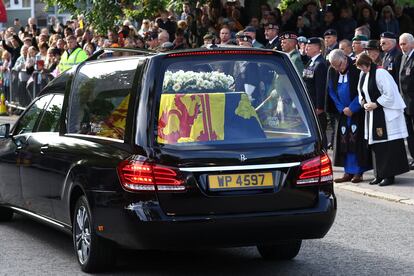 Vecinos de Ballater, cerca de Balmoral, muestran sus respetos tras el paso del coche fúnebre. El ataúd de roble de la soberana está cubierto con el estandarte real de Escocia y sobre éste se ha depositado un ramo de flores.