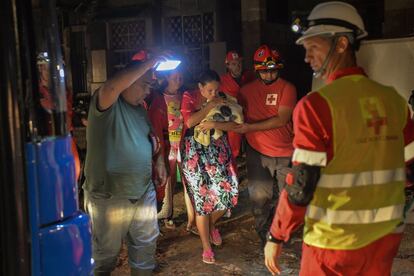 Membros dos serviços de emergência ajudam uma mulher e seu filho, depois do impacto de um tornado no bairro de Luyano, em Havana (Cuba).