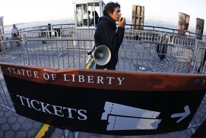 Un hombre anuncia de la clausura de la Estatua de la Libertad cerca del ferry que lleva a los turistas al monumento, 1 de octubre de 2013.