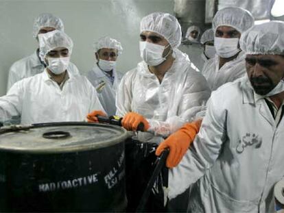Técnicos nucleares iraníes, junto a un bidón con productos radiactivos ayer en la central nuclear de Isfahán.