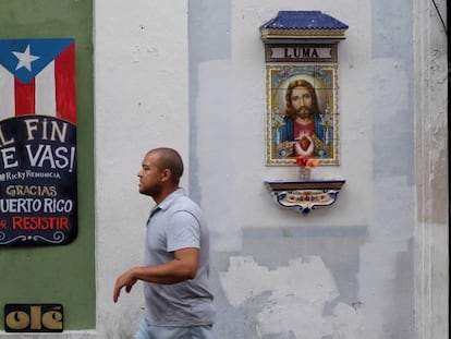 Um homem caminha junto a um cartaz que comemora a demissão do governador Ricardo Rosselló.