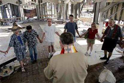 El reverendo Rob Dewey (de espaldas) dirige una oración entre ruinas, en Gulfport (Misisipí).