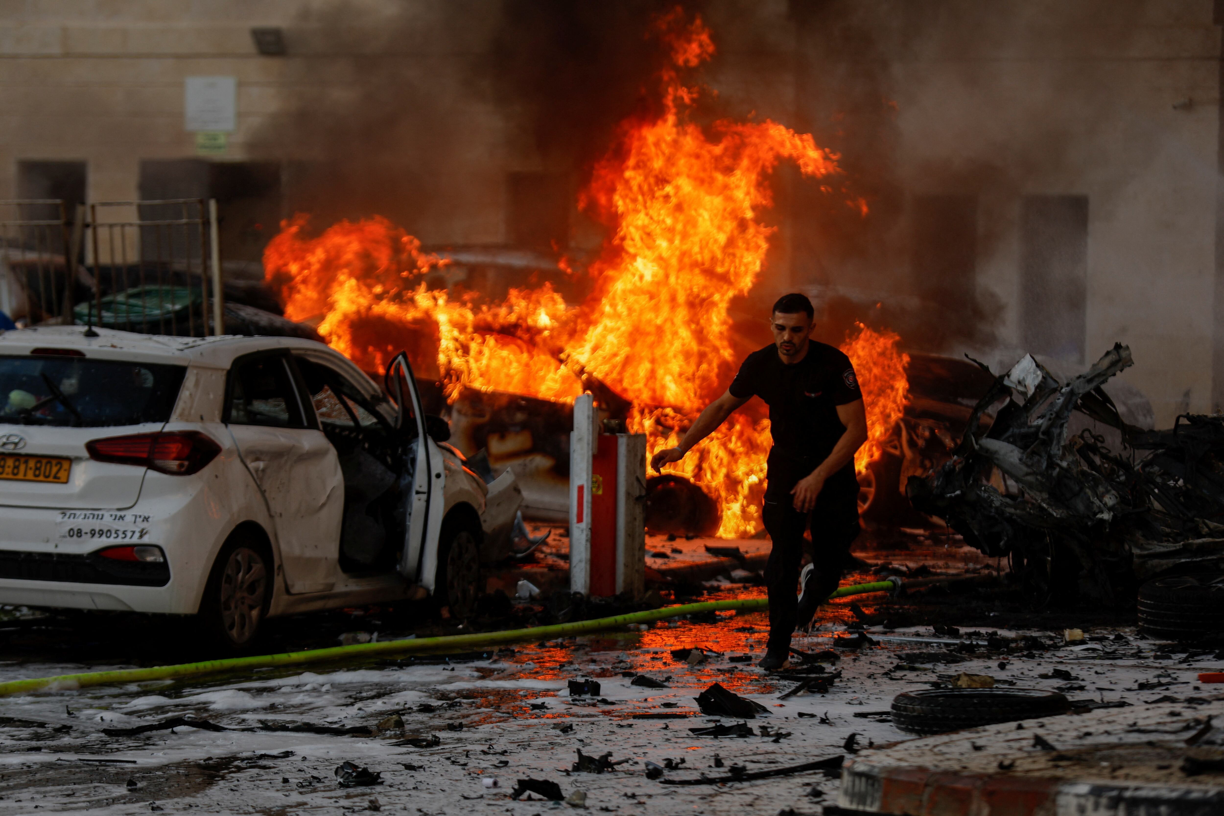 Un hombre huía de las llamas de varios coches incendiados tras el ataque con misiles palestinos, el sábado en la ciudad israelí de Ashkelón. 