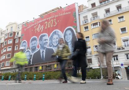 Tres mujeres caminan frente a la lona que han colgado las juventudes del PP en las inmediaciones de la sede del Partido Socialista, este jueves, en Madrid.