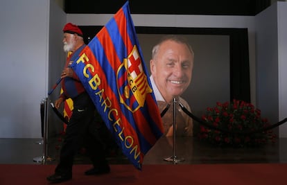 Un aficionat del Barcelona sosté una bandera del seu equip davant d'una imatge de Johan Cruyff al Camp Nou.