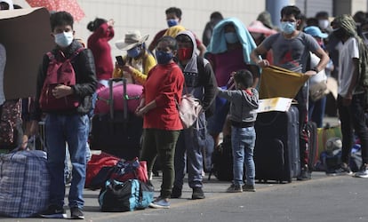 Un grupo de personas con mascarillas, en una parada de autobuses en Lima (Perú).