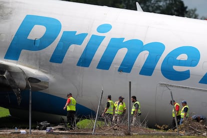 Unos trabajadores inspeccionan un avión de carga de Amazon dañado.