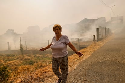 Una mujer se aleja del humo del incendio forestal en Santa Baia De Montes, este jueves.