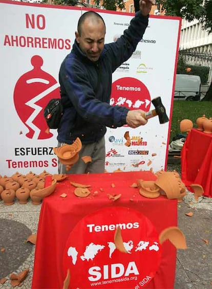 Un integrante de la ONG "tenemos Sida" rompe una hucha en la Plaza de Cibeles como símbolo de que se necesitan dejar e ahorrar esfuerzos en la lucha contra el sida. Cada día se infectan en España ocho personas por el VIH.