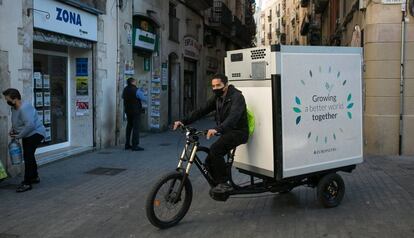 Un repartidor distribueix mercaderies congelades amb un tricicle elèctric al centre de Barcelona. 