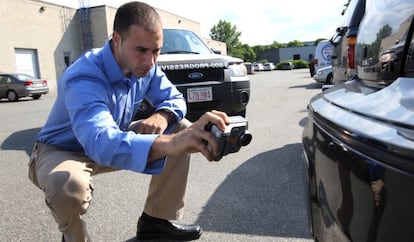 An insurance investigator inspects a car.