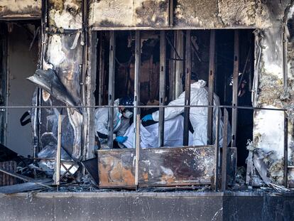 Bomberos y policía nacional trabajan en el edificio que fue devastado el jueves por las llamas.