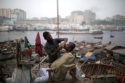 Un hombre se afeita en una barbería callejera en la orilla del río Buriganga en Dhaka (Bangladés).