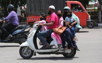 Una familia, protegida con mascarillas, viaja a bordo de una motocicleta, en Bangalore (India).