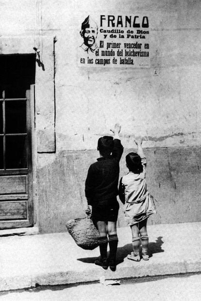 Dos niños saludan brazo en alto ante un cartel de Franco en septiembre de 1939.