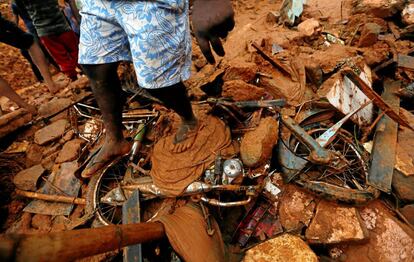Un hombre pisa una bicicleta dañada por el deslizamiento de tierra en la aldea de Bellana en Kalutara (Sri Lanka).