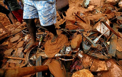 Un hombre pisa una bicicleta dañada por el deslizamiento de tierra en la aldea de Bellana en Kalutara (Sri Lanka).