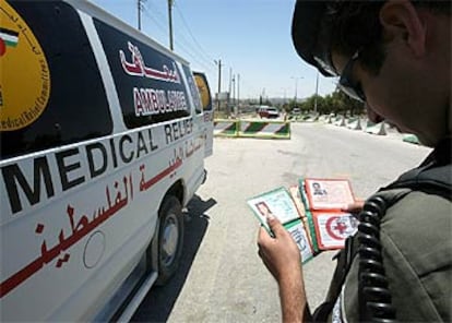Un policía israelí inspecciona la documentación de dos palestinos que trabajan en una compañía de ambulancias.
