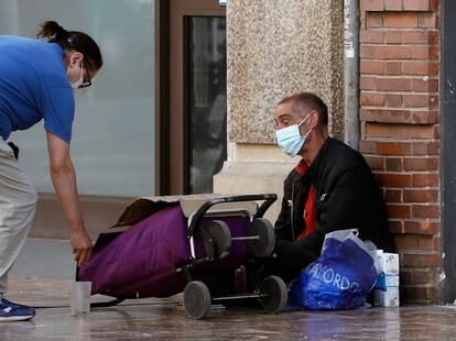 Una mujer da unas monedas a una persona sin recursos en Valencia.