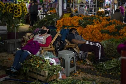 Dos vendedores de las tradicionales flores de cempasúchil duermen en su puesto del mercado de Jamaica ante la falta de clientes. En otros años para estas fechas los comerciantes de flores no se dan abasto ante la demanda.