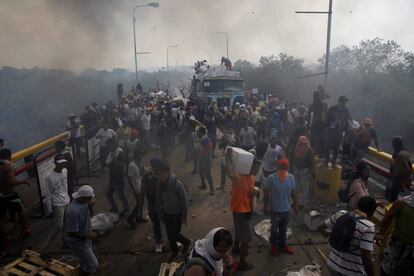 Miembros de la oposición descargan la ayuda humanitaria de un camión que fue incendiado sobre el puente Francisco de Paula Santander, en la frontera entre Colombia y Venezuela.