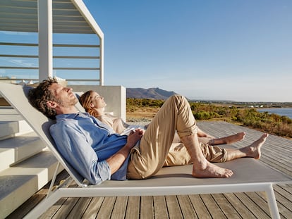 A couple lying on deck chairs at a beach house.