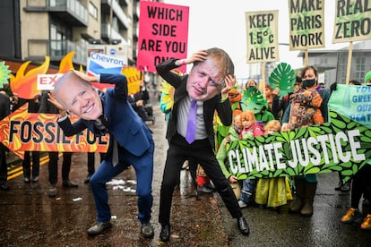 Activistas con máscaras de Joe Biden (izquierda) y Boris Johnson protestan a la entrada de la cumbre del clima, este viernes en Glasgow (Escocia).