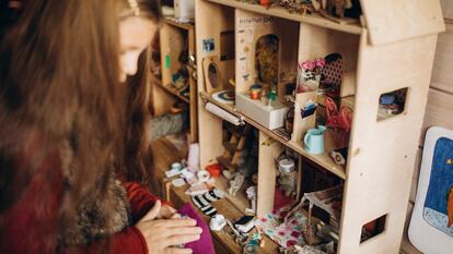 Una niña juega con una casa de muñecas.