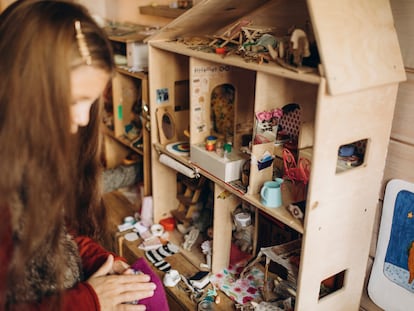 Una niña juega con una casa de muñecas.