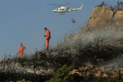 Dos bomberos apagan el fuego en la Sierra Calderona, ayer por la tarde.