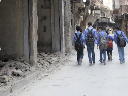 Estudiantes caminan en las calles repletas de escombros del campamento de refugiados de Yarmouk, Damasco, en 2020.