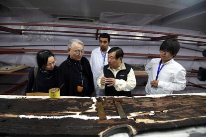 El egiptólogo japonés de la universidad de Waseda, Sakuji Yoshimura (centro), inspecciona una parte de la segunda barca funeraria del faraón Keops. La primera barca se encuentra en un museo.