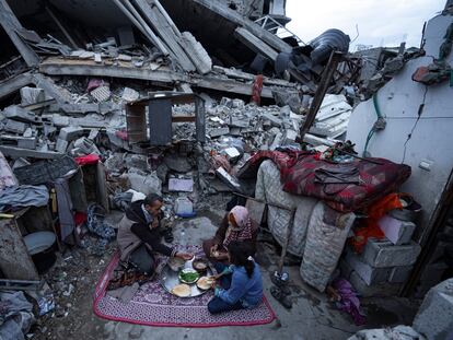 Miembros de la familia Al-Rabaya rompen el ayuno durante el mes del Ramadán frente a su casa destruida por los ataques aéreos israelíes en Rafah, este lunes.
