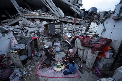 Miembros de la familia Al-Rabaya rompen el ayuno durante el mes del Ramadán frente a su casa destruida por los ataques aéreos israelíes en Rafah, este lunes.