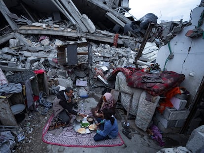 Miembros de la familia Al-Rabaya rompen el ayuno durante el mes del Ramadán frente a su casa destruida por los ataques aéreos israelíes en Rafah, este lunes.